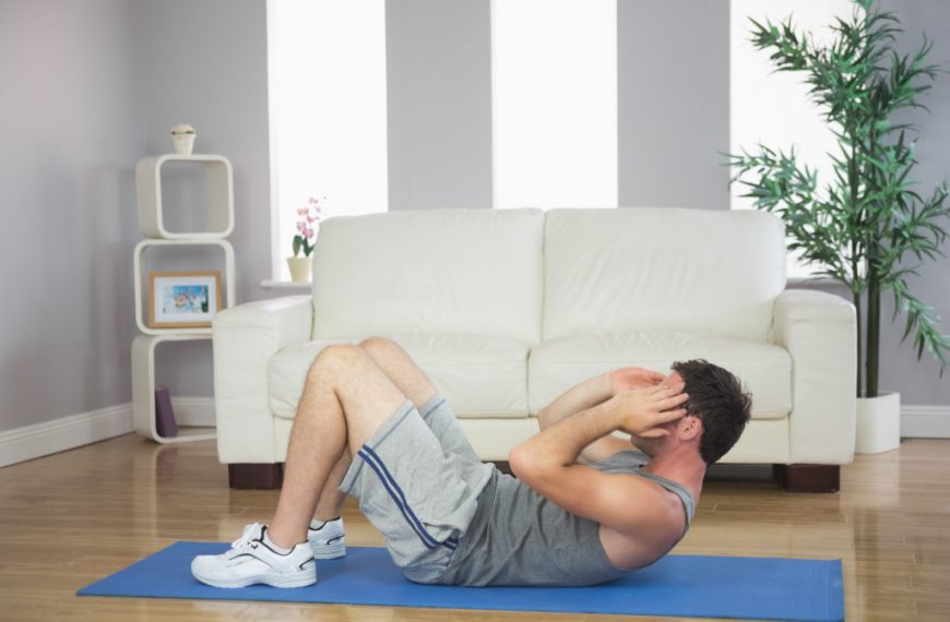 sporty man doing sit ups in bright living room